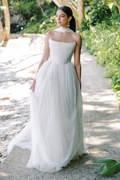 a woman in a white dress walking down a path