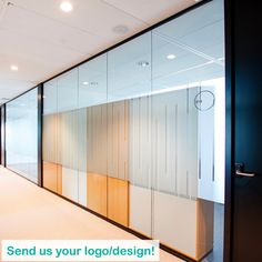 an empty office hallway with glass walls and wood paneling on the wall, along with a green sign that reads send us your logo design