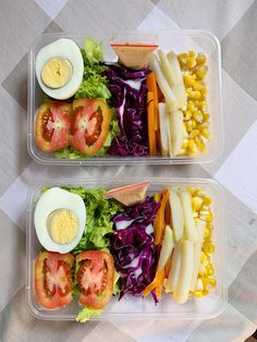 two plastic containers filled with salad and an egg on top of each container are sitting on a checkered tablecloth