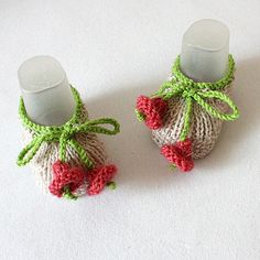 two crocheted baby booties with bows on the top and bottom, sitting next to each other