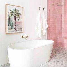 a white bath tub sitting next to a pink tiled wall in front of a shower