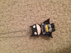 a necklace with a batman figure hanging from it's side on a carpeted surface