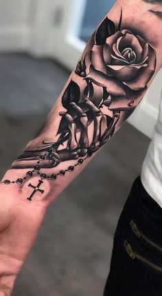 a person with a tattoo on their arm holding a cross and rose in the middle