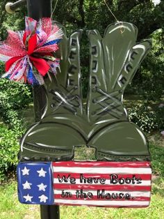 we have boots in the house sign hanging from a pole with an american flag on it