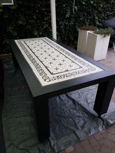 a black table with white designs on it sitting in the middle of a patio area