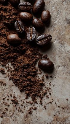 coffee beans and ground cocoa on a stone counter top with some spilled out of it