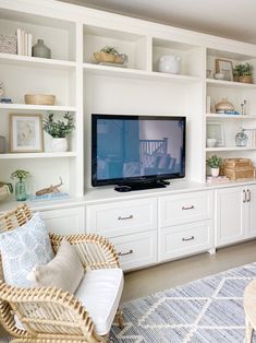 a flat screen tv sitting on top of a white entertainment center next to a wicker chair