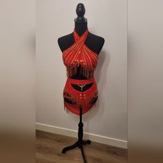 a mannequin dressed in red and gold with fringes on it's head