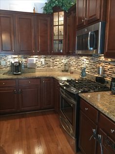 a kitchen with wooden floors and granite counter tops, dark wood cabinets and stainless steel appliances