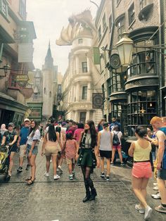 a group of people walking down a street next to tall buildings with dragon heads on them