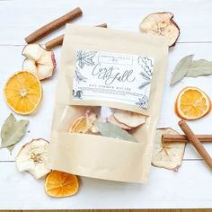 an assortment of dried fruits and spices on a white surface with cinnamon sticks, orange slices, and leaves