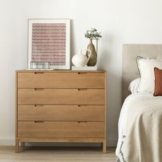 a bedroom scene with focus on the dresser and bed side table in the foreground