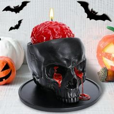 a black skull candle holder sitting on top of a table next to two pumpkins