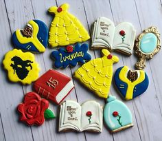 decorated cookies with beauty and the beast characters on them sitting on a white table next to an open book