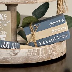 two wooden blocks with words on them sitting on a table next to a potted plant