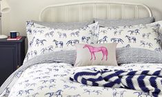 a bed with blue and white horse pillows on it