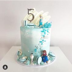 a birthday cake with frosting and decorations on it's top is decorated in blue, white and silver