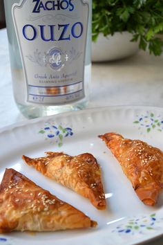 three pastries on a plate next to a bottle of alcohol