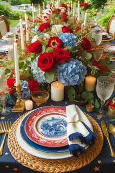 a blue and red table setting with flowers, candles, plates and napkins on it