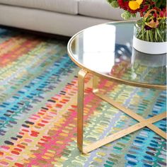 a living room with a couch, coffee table and colorful rug