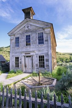 an old white house with a clock on the front