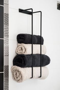 three towels are hanging on the wall next to a towel rack with black and white towels