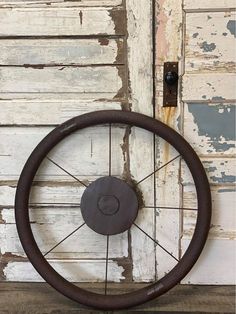 an old steering wheel hanging on the side of a building