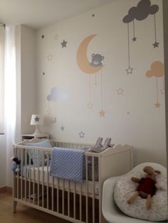 a baby's room with a crib and teddy bear on the wall next to it