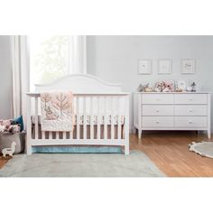 a baby's room with a white crib and dresser