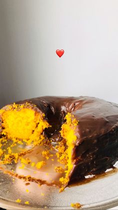 a chocolate cake with yellow frosting and a piece missing from it on a plate