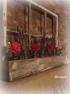 some red flowers are in vases on a window sill with an old brick wall behind them