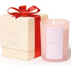 a pink candle next to a white box with a red ribbon