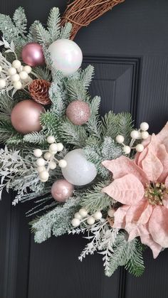 a christmas wreath with poinsettis, pine cones and other decorations on a door