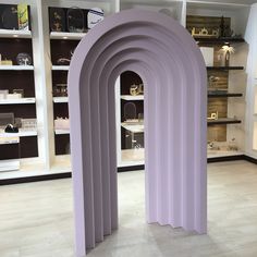 an arch shaped sculpture in the middle of a room with shelves and shelving behind it