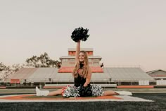 a cheerleader is sitting on the field with her pom poms in hand