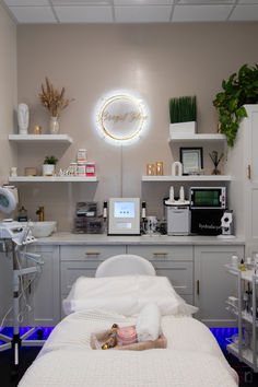 This Esthetician salon studio in Huntington Beach, California has a white theme with a unique lighting fixture to create a clean, warm feel. Esthetician Room Shelves, Esthetician And Nail Room, Wax Area In Salon, Esthetician Room Cabinets, Esthetician Room Lighting Ideas, Girly Esthetician Room, Beauty Salon At Home Ideas, Esthetician Room Wallpaper, Beauty Therapy Room Ideas