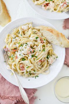 a white plate topped with pasta covered in sauce next to a glass of milk and two slices of bread