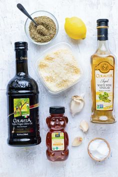 ingredients to make an italian salad laid out on a white surface with lemons, garlic and seasoning