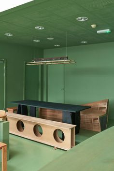 an empty room with green walls and wooden furniture on the floor in front of it