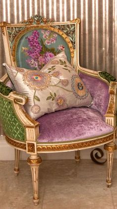 an ornate chair with pillows on it in front of a striped wallpapered room