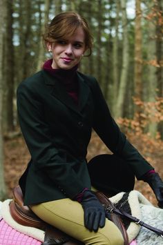 a woman riding on the back of a brown horse through a forest filled with trees