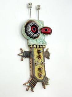 a metal wall hanging with a weird looking object on it's face and eyes