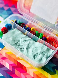 a plastic container filled with play dough on top of a colorful table