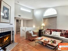 a living room filled with furniture and a fire place under a window next to a fireplace