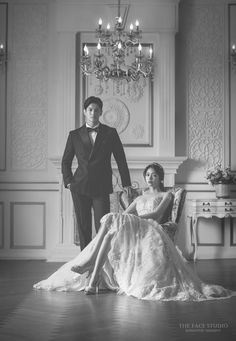 a man and woman in formal wear posing for a photo with chandelier above them