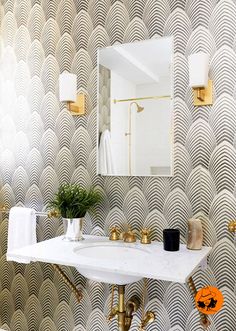 the bathroom is decorated in gold and white with an art deco wallpaper pattern on it