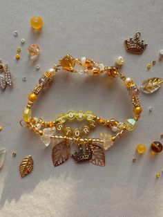 several bracelets with charms and beads on top of a white surface, including leaves