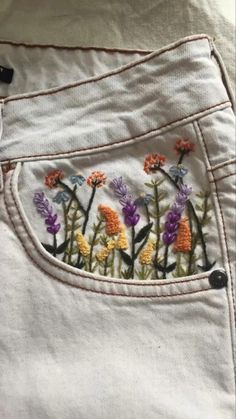 a pair of white jeans with embroidered flowers on them