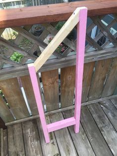 a pink wooden chair sitting on top of a wooden deck