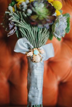 a bouquet of flowers sitting on top of a couch next to an orange sofa cushion